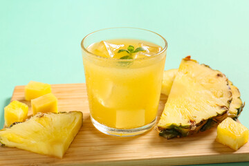 Glass of fresh pineapple juice with mint on turquoise background
