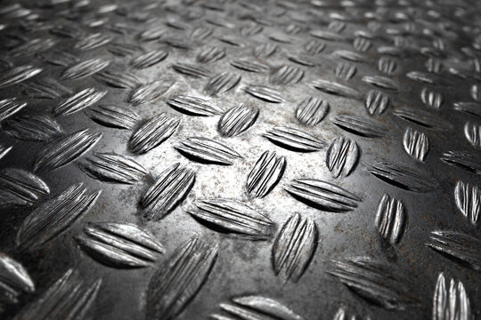 Close-up of a metallic, textured surface with raised, parallel lines and oval shapes.