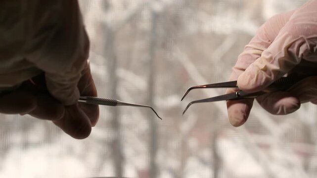 Hands performing delicate microsurgery procedure with surgical instruments in a dark room