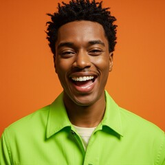 A young man with a bright smile and a vibrant green shirt against an orange background