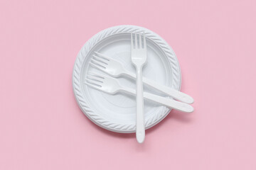 Plastic plate and cutlery on pink background