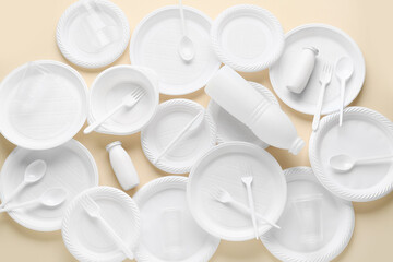 Different white plastic tableware on beige background