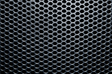Close-up of a metallic perforated grill with circular holes.