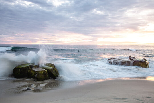 Cloudy evening sunset over La Jolla Califonia as waves crash upon rocks along the beach