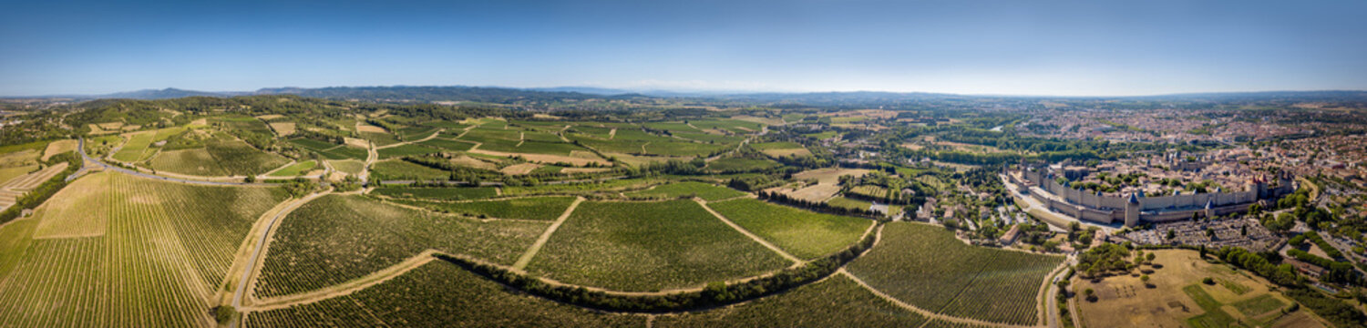 Ultra wide aerial panoramic view of the city of Carcassonne and its vineyards in the south of France. The old medieval city is lighten up by a winter sun