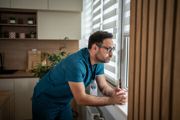 Healthcare worker looking out a window feeling worried