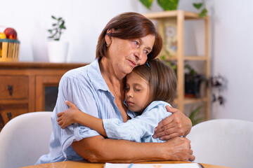 Grandmother comforting and hugging granddaughter with love and care at home, showing emotional support, family connection, and tenderness between generations