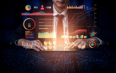 A businessman is engaged in data analysis using a digital display featuring graphs and charts in a modern office setting during nighttime. Impute