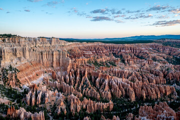 A beautiful landscape of red rock formations with a blue sky in the background. The sky is filled with clouds, giving the scene a serene and peaceful atmosphere