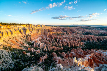 A beautiful landscape of red and white rocks with a blue sky in the background. The sky is clear and the sun is setting, creating a warm and peaceful atmosphere