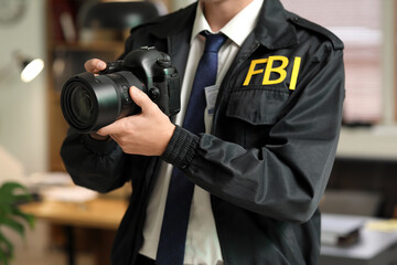Male FBI agent with photo camera in office, closeup