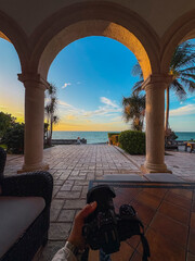Fototapeta premium POV photograph with arms and a camera to capture the beautiful sunset on the beach of Santorini, Greece. 