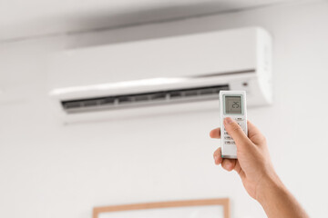Young man turning on air conditioner at home, closeup