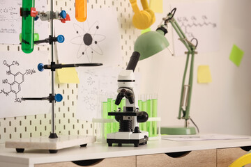 Modern microscope, chemical flasks on table and mood board in teenager's room
