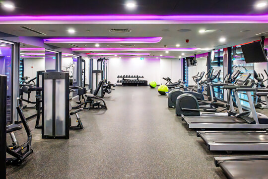 The interior of a well equipped gym and exercise facility featuring cardio machines, treadmills, elliptical, strength machines and free weights.