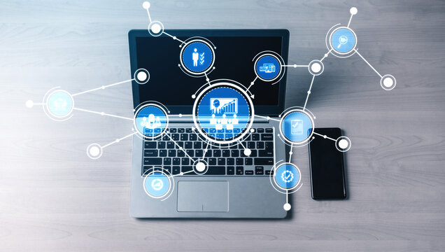 A modern laptop on a wooden desk displays digital network graphics that illustrate key business connections and data analytics, symbolizing technological advancement. Tessel - Powered by Adobe