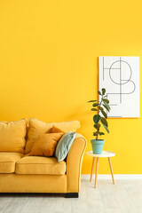 Interior of stylish living room with cozy sofa, picture and houseplant