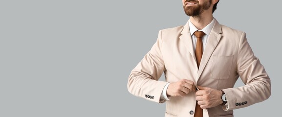 Handsome businessman buttoning jacket on light background with space for text