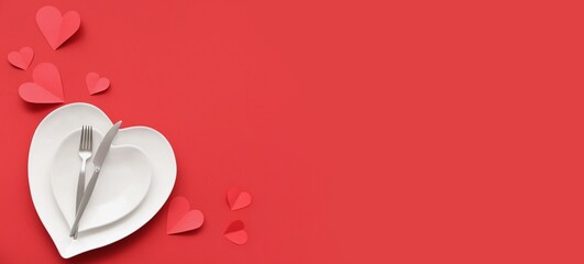 Table setting for Valentine's Day with paper hearts on red background with space for text
