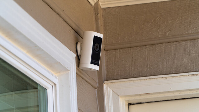 White outdoor smart security camera mounted on a residential house corner for 24-7 surveillance and property monitoring.