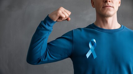 Young man in blue shirt flexing bicep with a blue awareness ribbon pinned to his chest