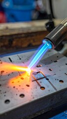 Torch flames melt metal plate, creating intense heat with blue to orange glow on workbench