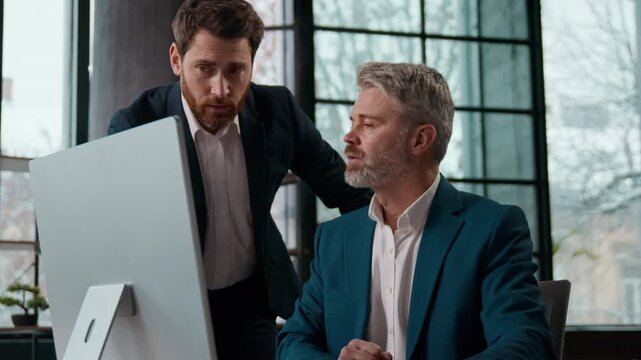 Two businessmen in office manager work on computer talking bad news bankruptcy stressed Caucasian men guys males business partners colleagues corporate dismissal failure online project shocked result