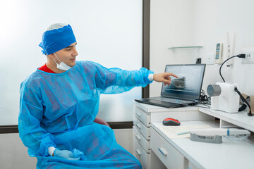 Naklejka premium Dentist analyzing patient dental x-ray on laptop in clinic