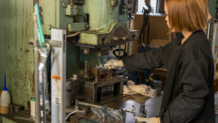 Industrial worker setting metal parts into press mold at manufacturing factory