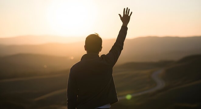 man with arm raised waving hello greeting sunlit landscape sunset or sunrise beautiful view from hill peaceful serene moment looking out over valley golden hour inspiring hopeful gesture