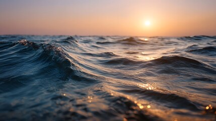 Gentle ocean waves ripple under a warm glowing sunset sky casting golden reflections on the water s surface