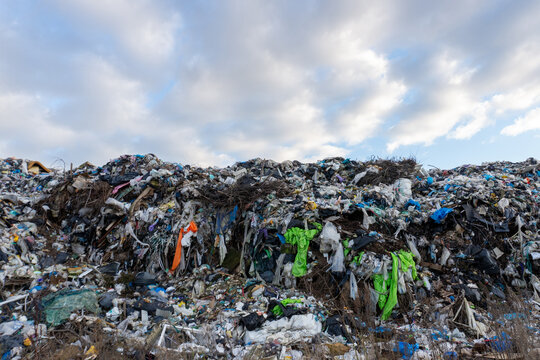 Large pile of trash at a landfill site under a cloudy sky during the day