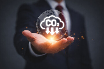 Businessman holding glowing CO2 emission icon symbolizing carbon footprint climate impact environmental responsibility sustainability and green business strategy concept