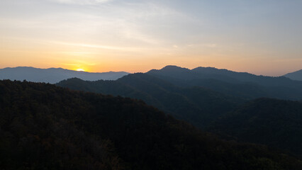 Obraz premium The image shows mountains in the foreground with the sun rising in the background.