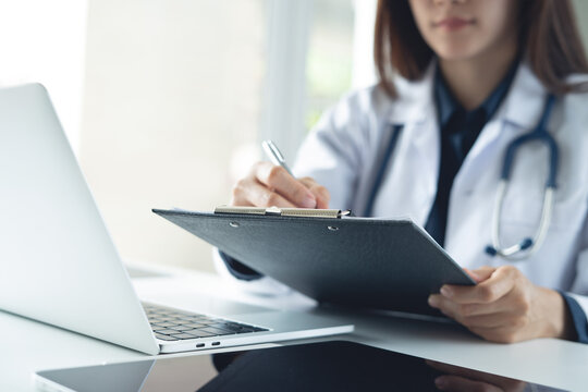 Asian femal doctor writing notes on clipboard for hospital schedule, history record or healthcare checklist. Doctor writing prescription, medication document for patient in hospital office