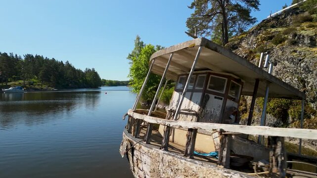 Abandoned decaying wooden boat sits in shallow lake water in K&ouml;pmannebro Sweden during aerial passing drone shot showing rusted textures and natural decomposition
