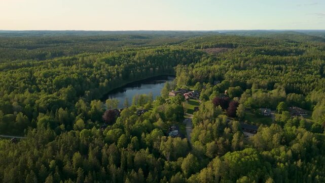 Drone flying forward over Kroppefj&auml;ll nature reserve with a slow tilt down revealing dense evergreen forest and scattered houses near Dals Rostock Mellerud Sweden during summer