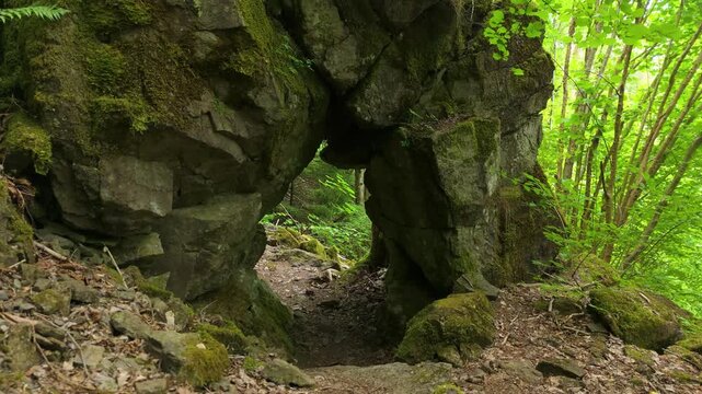 Approaching a narrow rock passage covered in green moss and lichen in Kroppefj&auml;ll wilderness near Dals Rostock, Sweden, forest landscape
