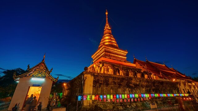 A sacred royal Buddhist temple in Nan, Thailand, featuring a glowing golden stupa during blue hour. Wat Phaya Phu Phra Aram Luang represents spiritual devotion, historic architecture and the cultural