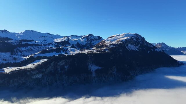 Wide-angle aerial panorama capturing the vast mountain range of Central Switzerland under a deep blue sky with fog in the valleys.