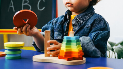 Child learning with colorful wooden educational toy in classroom