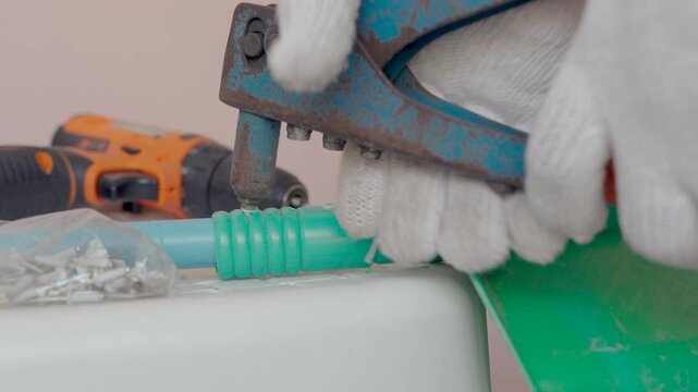 Close-up hand of man use rivet gun or rivet pliers to repair the plastic dustpan. attach rivets with PVC pipe.
