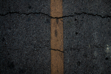 Textured close-up of cracked pavement surface emphasizing road wear and deterioration.