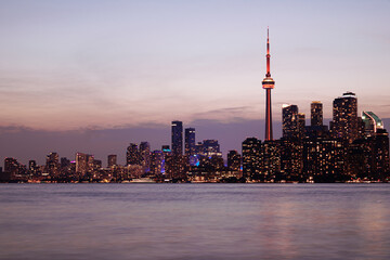 Naklejka premium Toronto skyline at dusk with illuminated city lights reflecting on the water, vibrant urban night view. g.