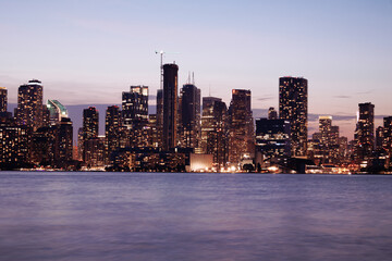 Naklejka premium Toronto skyline at dusk with illuminated city lights reflecting on the water, vibrant urban night view. g.