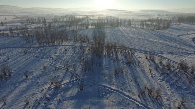 Aerial drone view of a vast Central Asia flat plain landscape during a snowy winter sunrise. The frozen grassland, icy steppe, and bare plateau create a beautiful, cinematic, cold weather background s