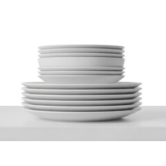 A clean stack of white ceramic plates and bowls arranged neatly on a white shelf. The image features soft studio lighting against a white background.