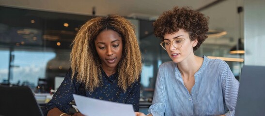 Diverse women collaborating on document discussing business strategy
