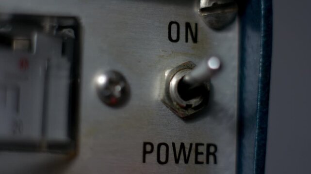 Close-up of a mechanical power switch being turned on on a vintage laboratory power supply, symbolizing activation, control and electrical startup in technical equipment.