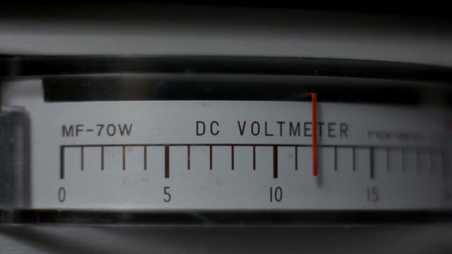 Close-up of an analog DC voltmeter on vintage laboratory power equipment, showing the needle rising from zero to twelve volts, symbolizing electrical testing, power control and technical measurement.